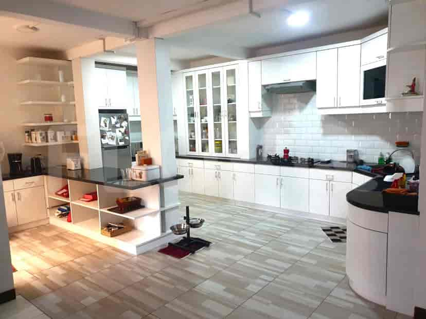 A modern kitchen with white cabinets, black countertops, and integrated appliances.