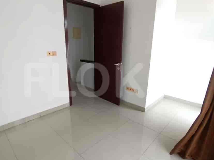 A bedroom with white walls, tiled floors, and a closed door.