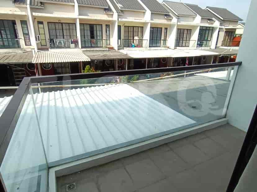 A balcony with a glass railing overlooking a neighborhood.
