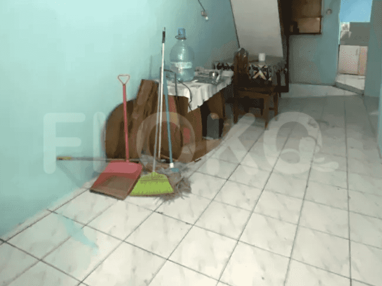 A hallway with tiled floors, teal walls, and cleaning supplies.