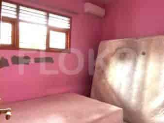 Kamar tidur dengan kasur di lantai, jendela, dan dinding berwarna merah muda.