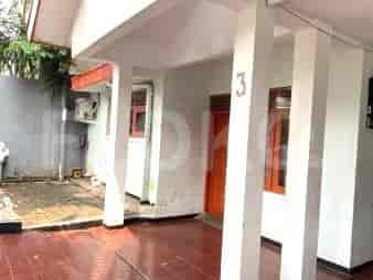 Eksterior rumah dengan teras tertutup, pintu masuk, dan pilar.