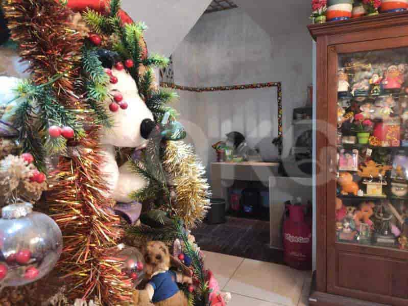 A living area with a Christmas tree, cabinet and view of another room.