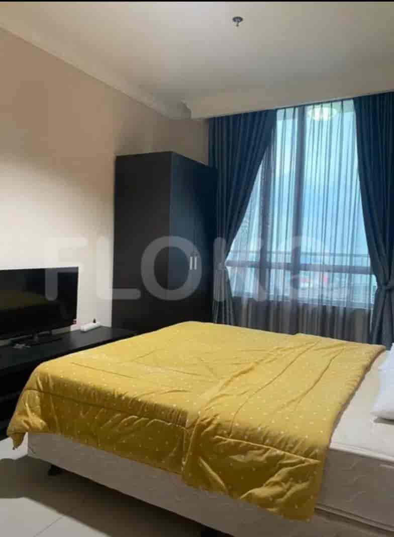 A bedroom featuring a bed with a yellow comforter, a dark wardrobe, and a window with curtains.