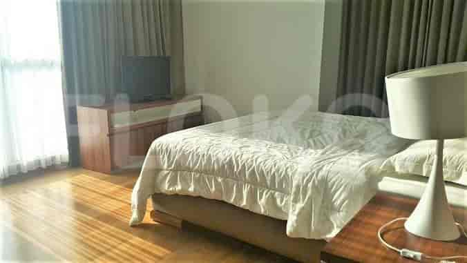 A bright bedroom with a bed, TV, and window.