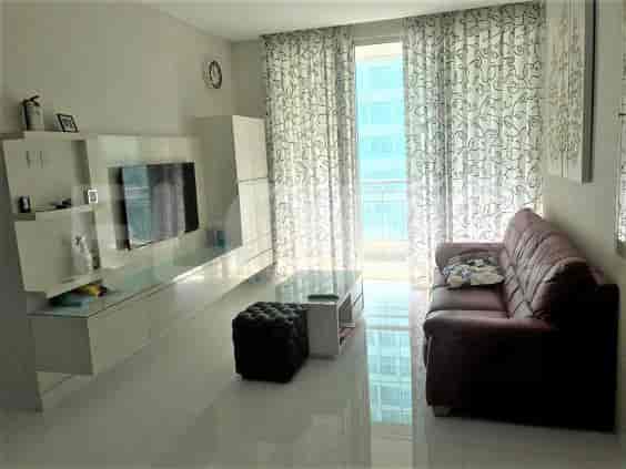 A modern living room with a TV, sofa, and a view through sheer curtains.