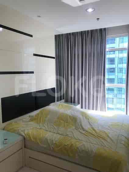 A bright bedroom featuring a bed, nightstands, and curtains.