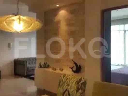 Ruang tamu dan ruang makan dengan sofa, dinding dekoratif, dan lampu gantung.