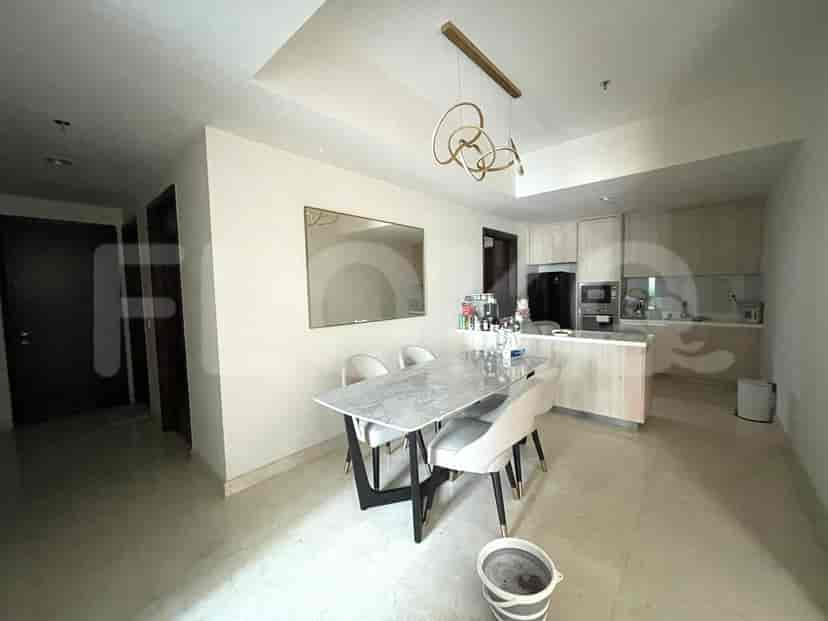 A dining area with a marble table and chairs, open to a modern kitchen with light wood cabinetry.