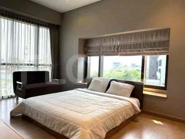 Bedroom with a queen bed, large windows, and a seating area.