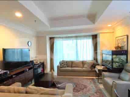 Ruang tamu yang luas dengan sofa coklat muda, TV besar, dan akuarium.