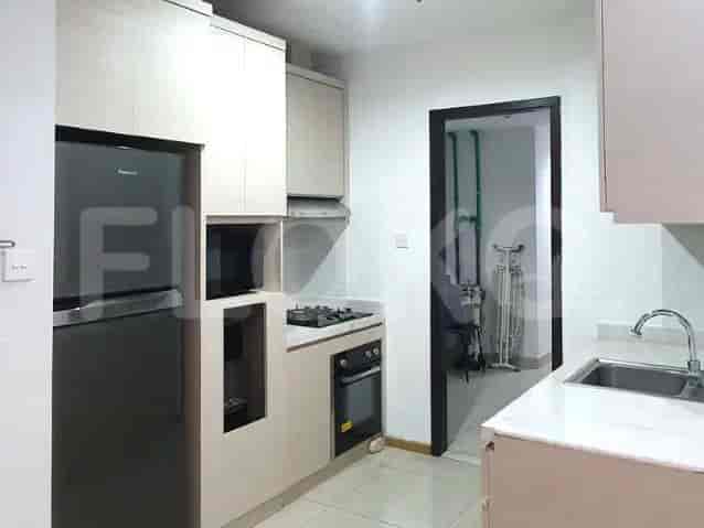 A modern kitchen with a black refrigerator, overhead cabinets, and built-in appliances.