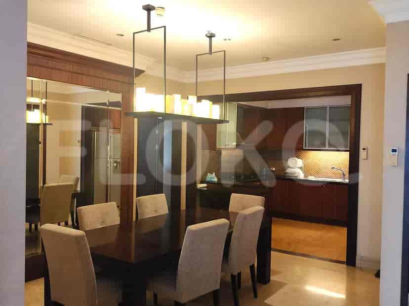The dining area includes a wooden dining table with six chairs and an open kitchen in the background.