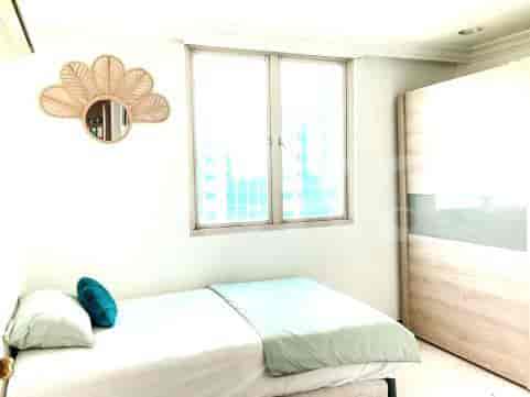 A bright bedroom with a single bed, window, and wardrobe.