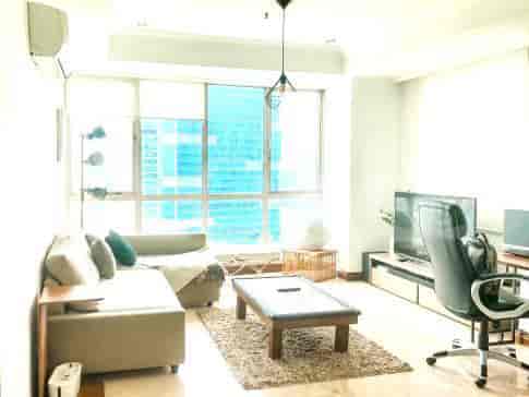 A bright living room featuring an L-shaped sofa, a coffee table, and large windows.