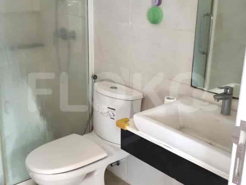 A well-lit bathroom with a glass-enclosed shower, a white toilet, and a sink.