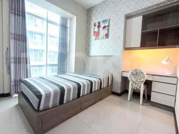 Kamar tidur modern dengan tempat tidur tunggal, laci built-in, meja, dan jendela besar.