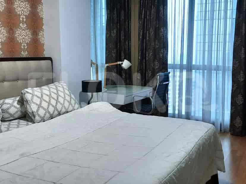 A bedroom with a bed, desk, and window with curtains.