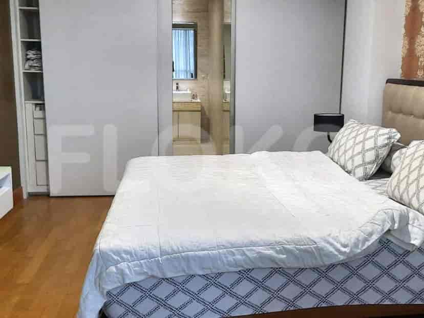 A well-lit bedroom featuring a large bed, sliding door closet, and a bathroom.