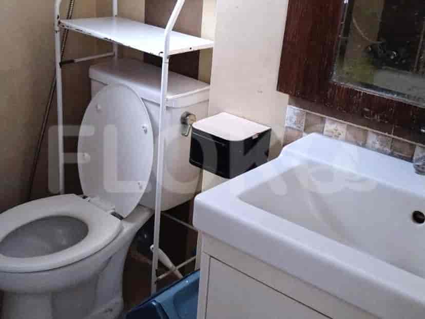 A bathroom with a toilet, sink, and shelf.
