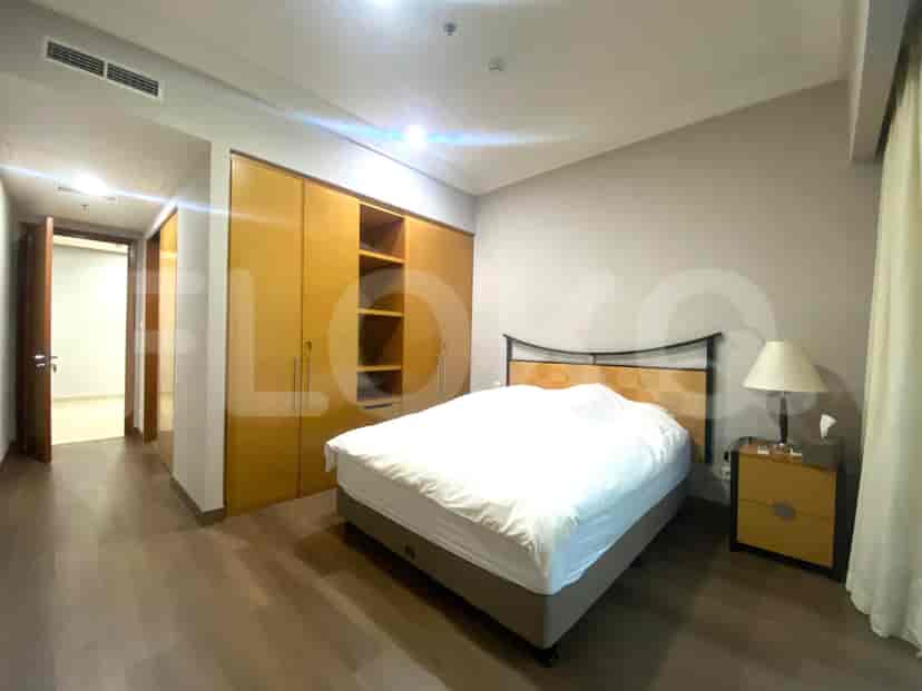 A bedroom with a bed and wooden cabinets.