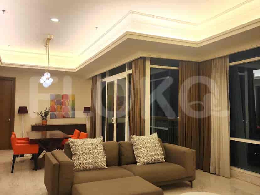 Living room with a sofa, dining table, and a view through large windows.