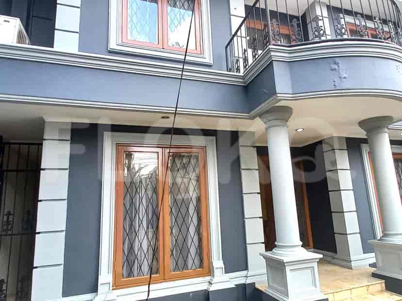 A multi-story house with grey walls, large windows, and a balcony.