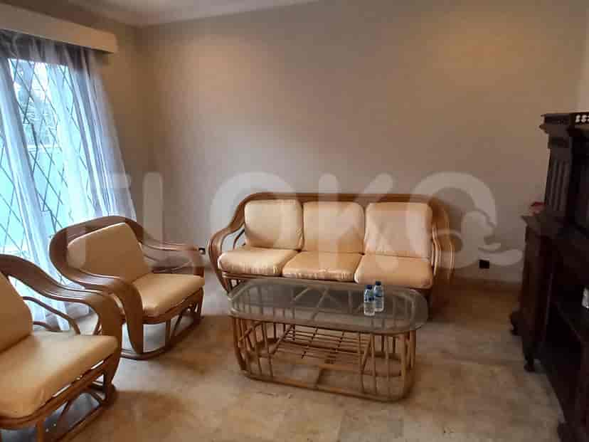 A living room with a rattan sofa, two chairs, and a glass-top coffee table.