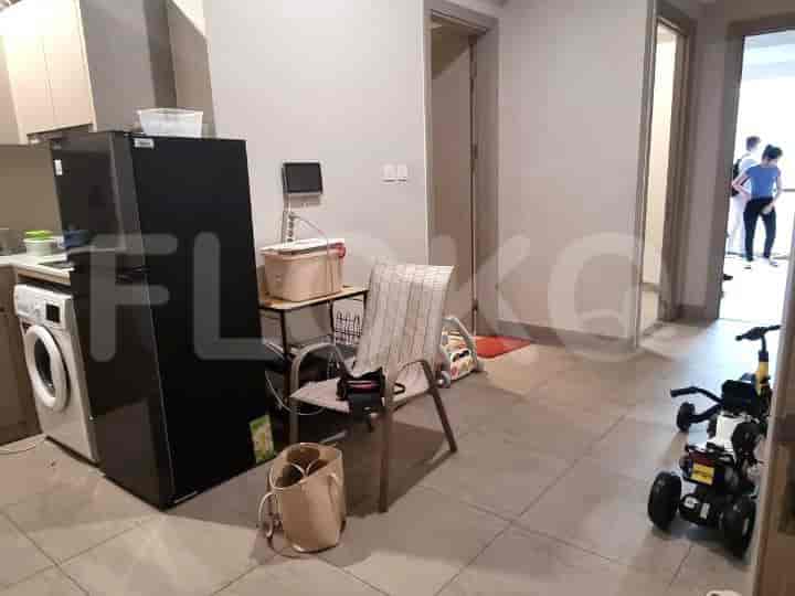 A kitchen area with a fridge, washing machine, and seating.