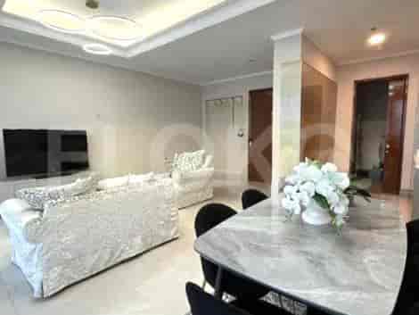 Ruang tamu yang terang benderang dengan sofa, meja makan, dan TV.