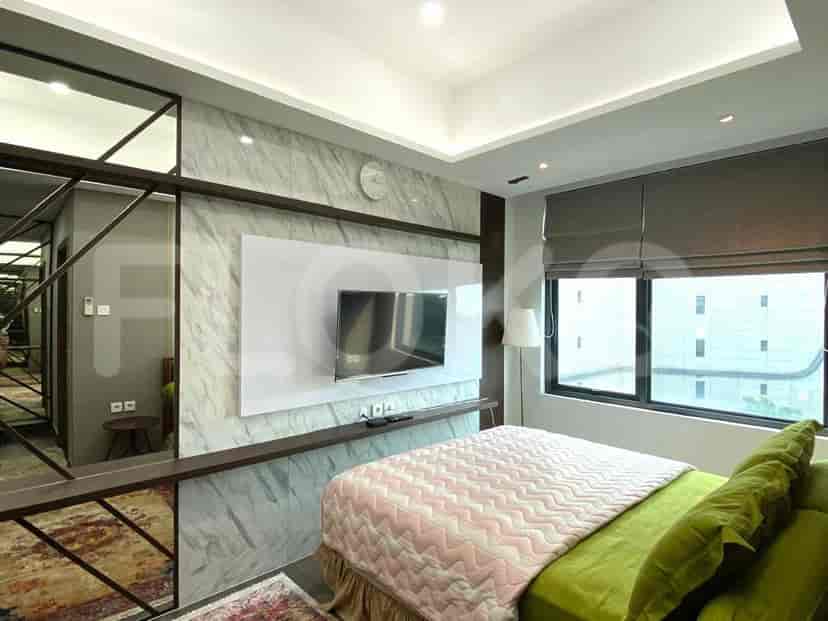 Kamar tidur utama dengan tempat tidur, TV, dan dinding aksen dengan cermin dan efek marmer.