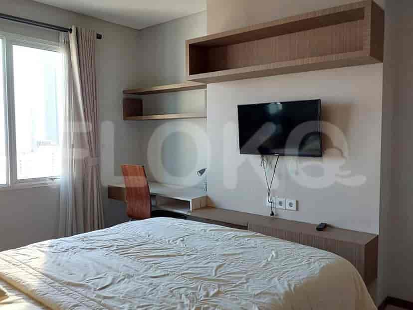Kamar tidur modern dengan tempat tidur ukuran queen, meja, dan TV yang dipasang di dinding.