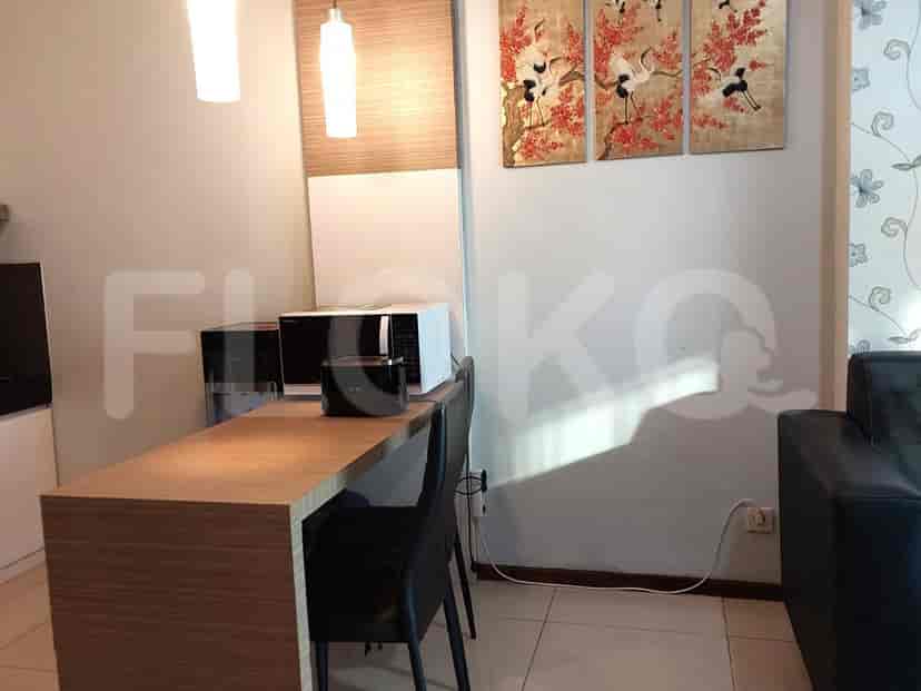 Pemandangan area makan dengan microwave dan sofa kecil.
