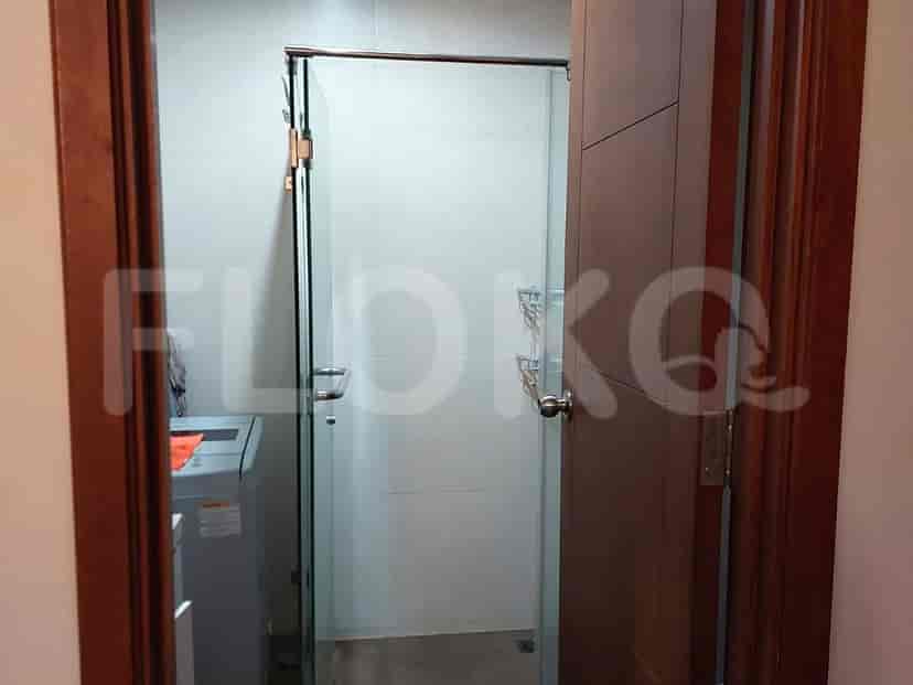 Kamar mandi dengan pintu kaca dan mesin cuci terlihat.