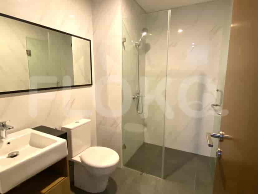 Kamar mandi modern dengan pancuran kaca, dinding marmer putih, dan meja rias.