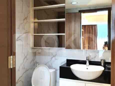 A bathroom with a marble accent wall, mirror, and white fixtures.