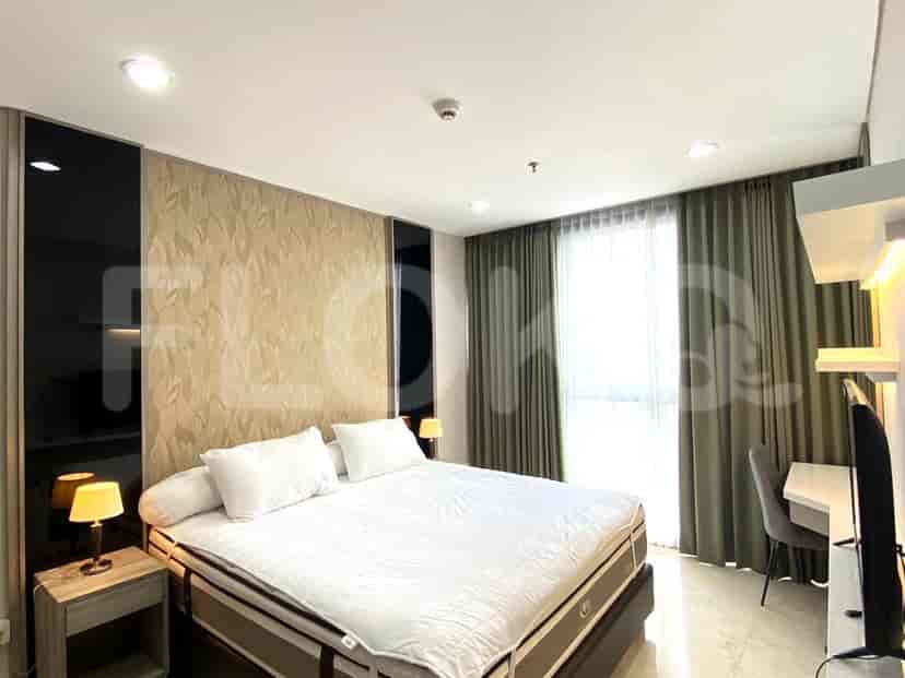 A modern bedroom featuring a king-size bed, bedside lamps, and a work desk with a chair.