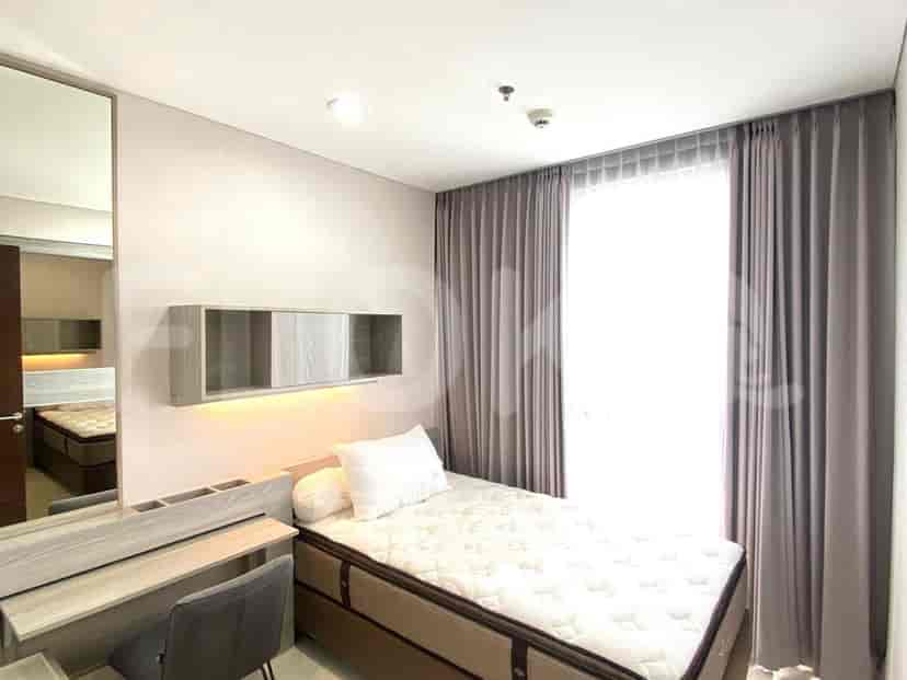A cozy bedroom with a single bed, a desk, and a large window for natural light.