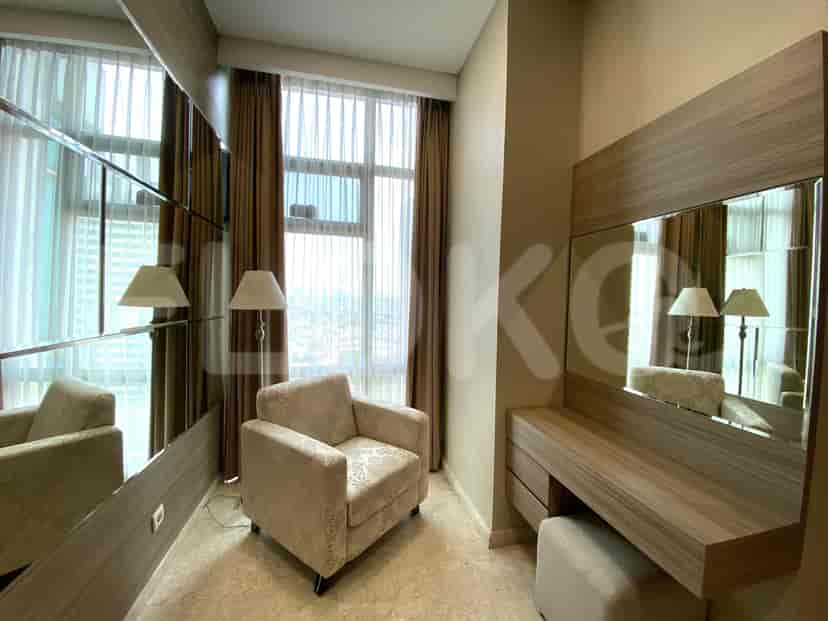 A bedroom with a dressing table, an armchair, and a large mirror.