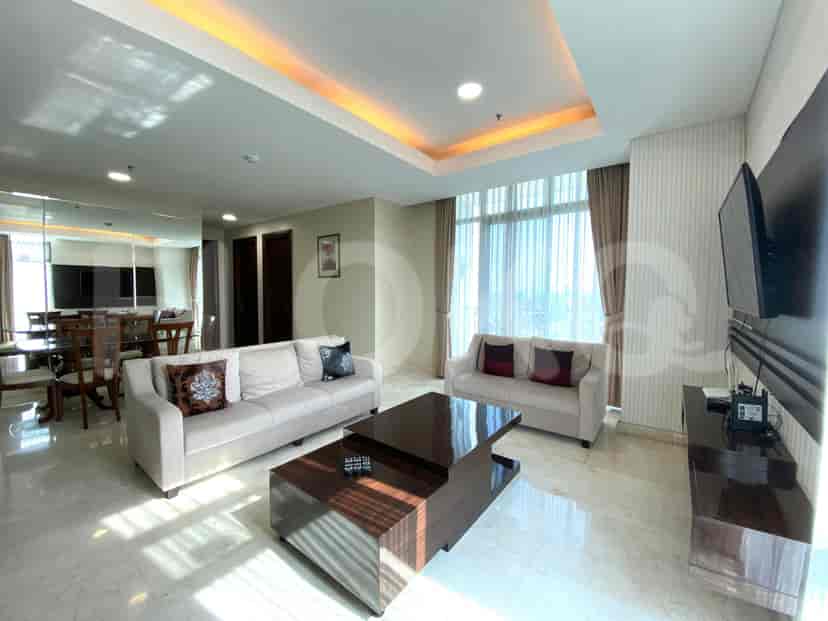 Spacious living room with beige sofas, a dark wood coffee table, and large windows with curtains.