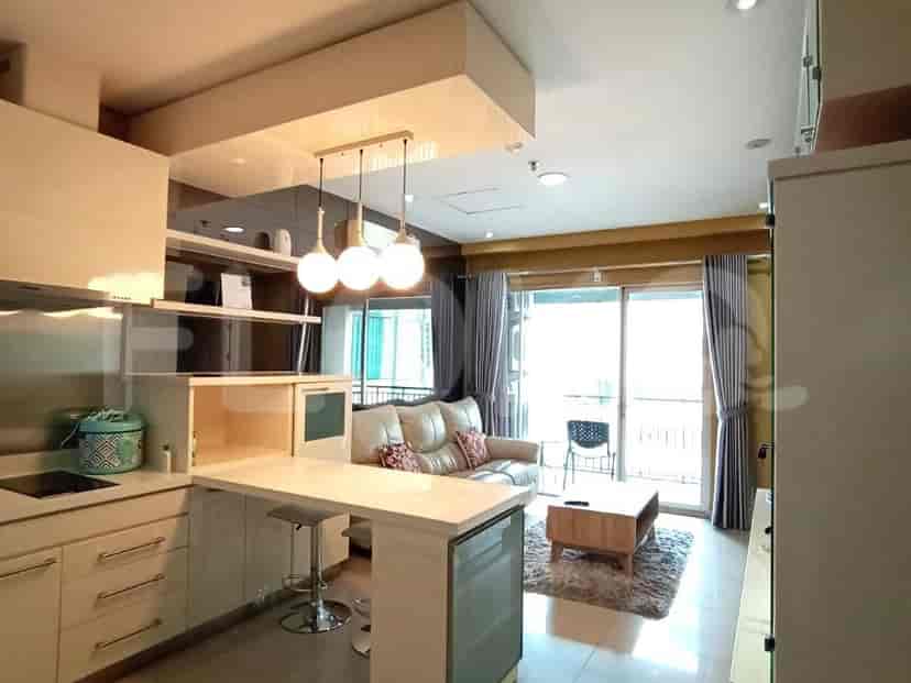 An open-plan living space showcasing a kitchen, sofa, and a sliding glass door leading to a balcony.