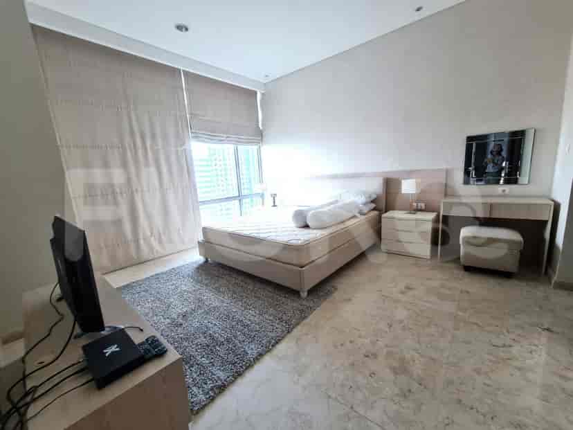 A bedroom featuring a bed, a TV, and a vanity table.