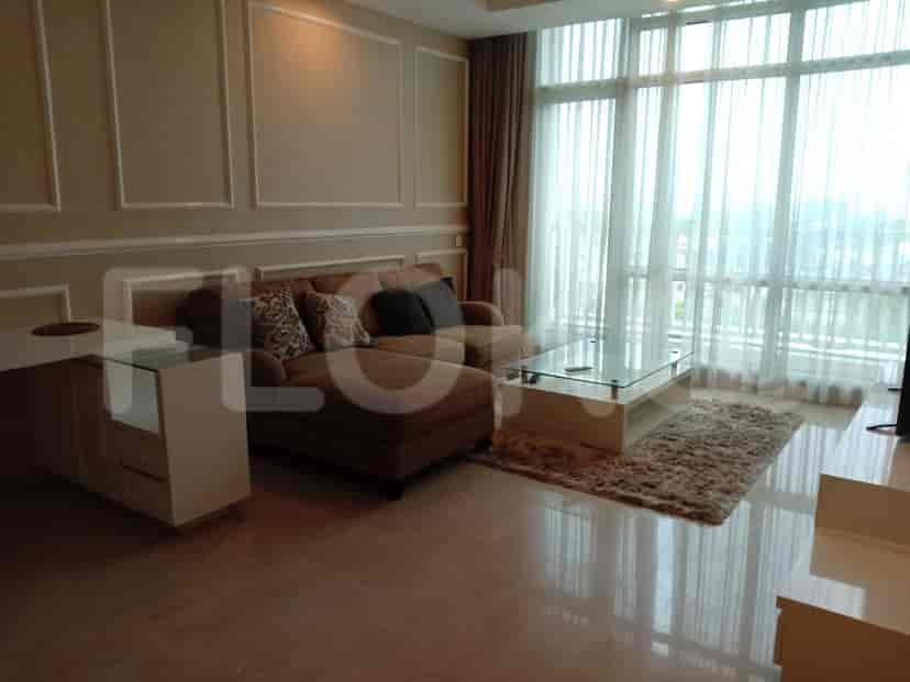 Living room with a sofa, coffee table, and a view of the city through large windows.