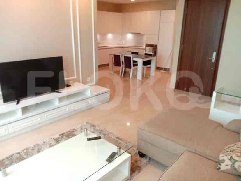 Living room with a TV, sofa, and a peek at the kitchen.