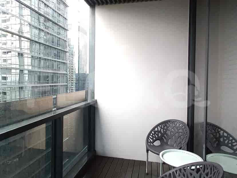 Small balcony with chairs and a view of surrounding buildings.