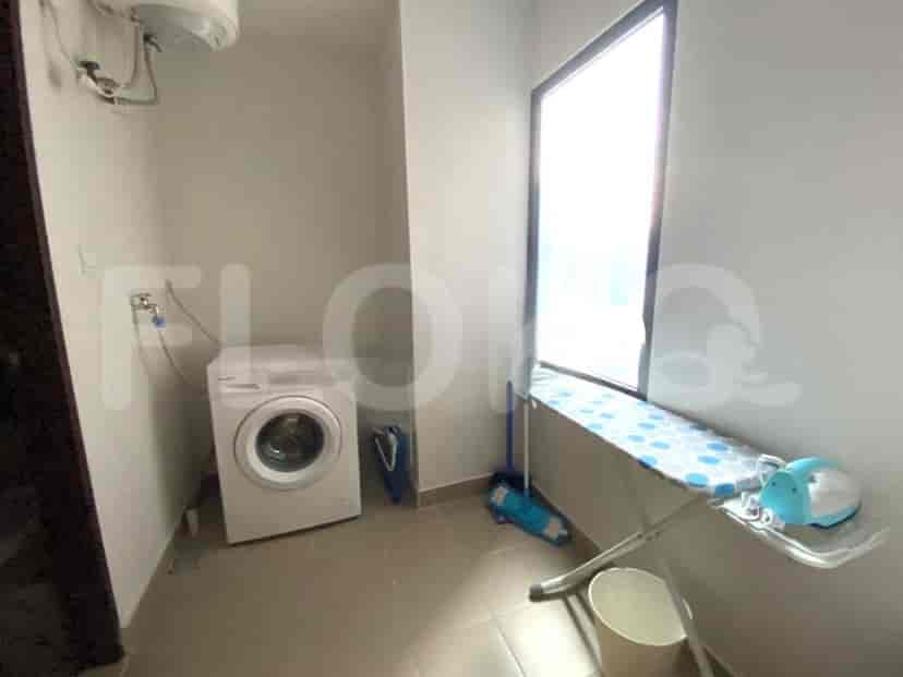 A laundry room equipped with a washing machine, an ironing board, and a window.