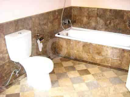 A bathroom with a toilet, bathtub, and tiled floors and walls.