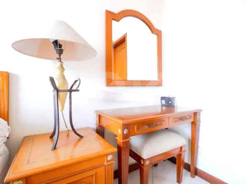 A bedroom with a vanity, table, and mirror.