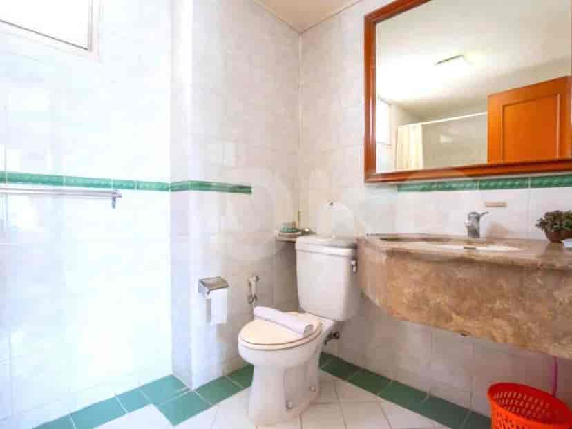 A bathroom with a toilet, sink, and mirror.