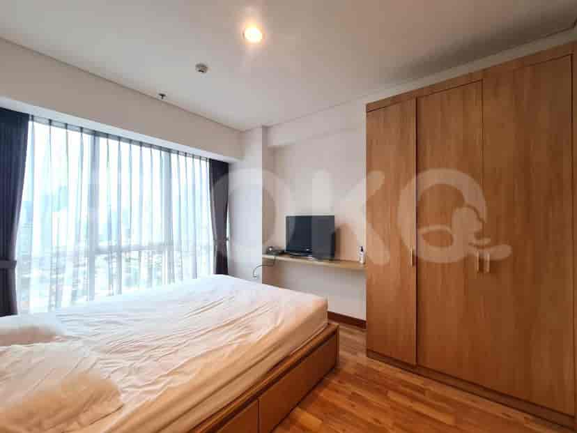 Bedroom with a large bed, closet, and large window with curtains.